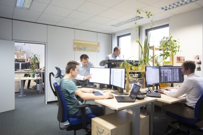 Kollegen im Büro helfen sich gegenseitig und schauen auf ihre Bildschirme